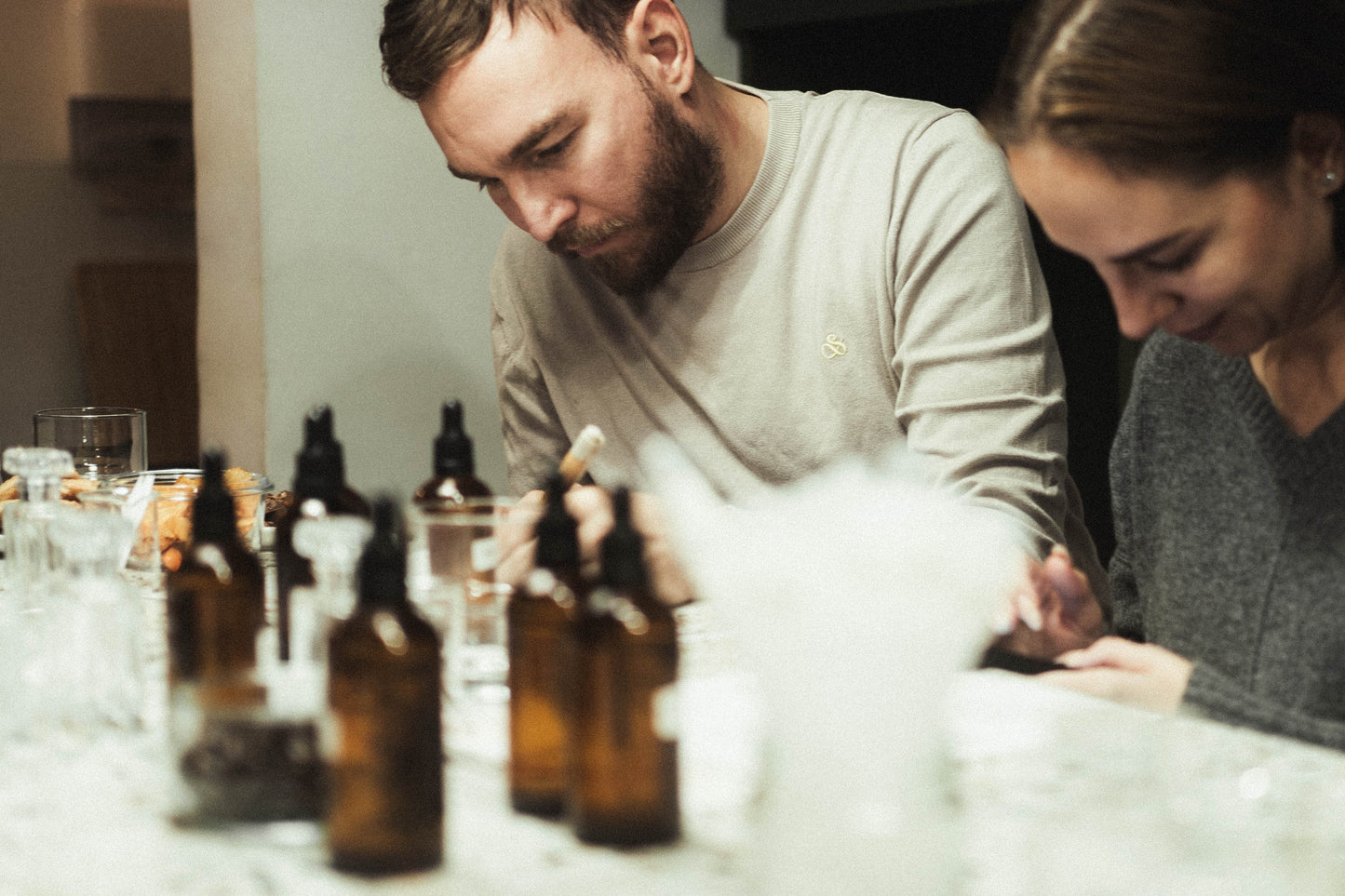 A couple sitting at a table with several brown glass bottles in front of them.