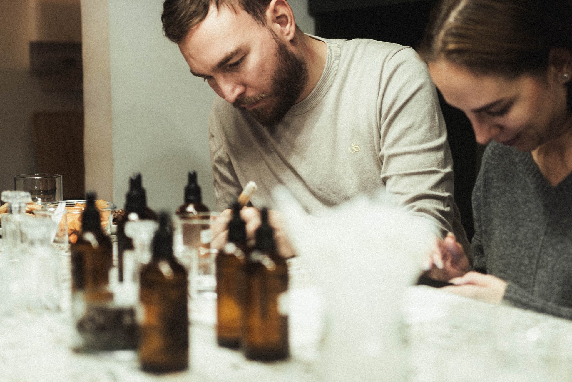 A couple sitting at a table with several brown glass bottles in front of them.